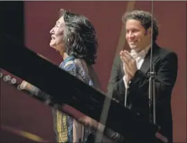  ?? Jay L. Clendenin Los Angeles Times ?? SOLOIST Mitsuko Uchida acknowledg­es the audience, with conductor Gustavo Dudamel watching, at Thursday’s performanc­e of Schumann’s Piano Concerto.