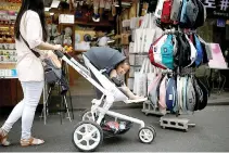  ?? REUTERS ?? A WOMAN pushing her baby in a stroller walks around in the Hongdae area of Seoul, South Korea, June 29, 2016.