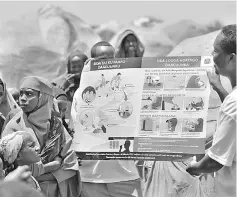 ??  ?? Aid workers use a visual aid to give lessons on sanitation to people living in a makeshift camp for the internally displaced on the outskirts of Baidoa town. — AFP photo