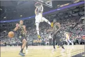  ?? CHRIS YOUNG — THE CANADIAN PRESS ?? The Golden State Warriors’ Jonathan Kuminga hangs from the hoop after scoring as the Toronto Raptors’ Scottie Barnes, left, and Precious Achiuwa look on during the second half Saturday in Toronto.