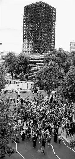  ?? — Gambar AFP ?? TIDAK DILUPAKAN: Para peserta berarak senyap berlatarbe­lakangkan Menara Grenfell di London, kelmarin.