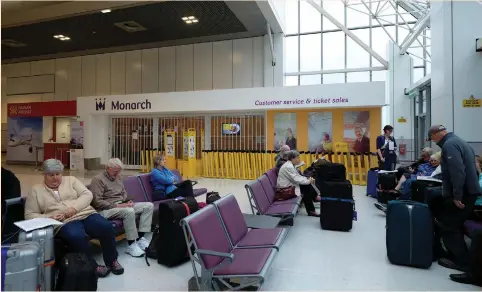  ?? (Andrew Yates/Reuters) ?? PASSENGERS SIT outside a Monarch airlines customer-service office at Manchester Airport yesterday after the airline went out of business. Its demise added to turbulence in the European airline industry after Air Berlin and Alitalia filed for insolvency...