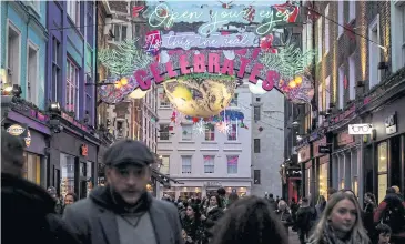  ?? AFP ?? People walk past Christmas decoration­s on Carnaby Street.