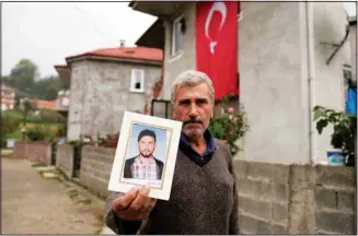  ?? ?? Recep Ayvaz, 62, shows a picture of his son, Selcuk Ayvaz, 33, one of the miners killed in a coal mine explosion, in front of his house in Amasra, in the Black Sea coastal province of Bartin, Turkey, Sunday, Oct. 16. (AP)