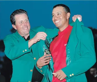  ?? ASSOCIATED PRESS FILE PHOTO ?? In this April 10, 2005, photo, Tiger Woods, right, gets the Green Jacket from Phil Mickelson after winning the Masters at the Augusta National Golf Club in Augusta, Ga.