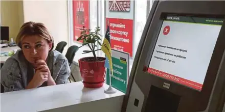  ??  ?? An employee sitting next to an out-of-order payment terminal at a branch of Ukraine’s state-owned bank Oschadbank that was hit by cyberattac­ks yesterday. REUTERS PIC