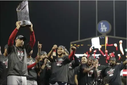  ?? PHOTO/DENIS POROY ?? Boston Red Sox manager Alex Cora holds the championsh­ip trophy after Game 5 of baseball’s World Series against the Los Angeles Dodgers on Sunday, in Los Angeles. The Red Sox won 5-1 to win the series 4 game to 1. AP