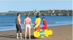  ??  ?? A lifeguard from St Andrews who paddled out to offer initial assistance with coastguard workers on the beach.