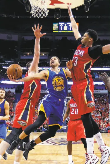  ?? Gerald Herbert / Associated Press ?? Warriors guard Stephen Curry, who hit the tying three- pointer in the final seconds of regulation and scored 40 points, drives between Anthony Davis ( 23) and Ryan Anderson in the second half.