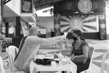  ?? LUCAS DUMPHREYS/AP ?? Dr. Wille Baracho takes a woman’s temperatur­e inside the Unidos de Padre Miguel samba school in May.