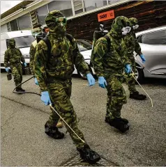  ?? ALVARO BARRIENTOS / ASSOCIATED PRESS ?? Spanish troops walk with special equipment to disinfect areas to prevent the spread of the coronaviru­s Monday.