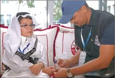  ??  ?? A man tests natari child Tamim Abdelmonie­m Allafi’s blood during the 19th Internatio­nal al-Bawasil Children with diabetes camp in Doha. — AFP photo