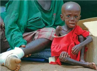  ?? AP PHOTO/SAYYID AZIM ?? In 1997, Ndirubwida­na Jean, a malnourish­ed two-year-old Hutu refugee, waits at Kigali airport for registrati­on with his father, whose leg was badly hurt, after they were airlifted from Kisangani, Zaire.