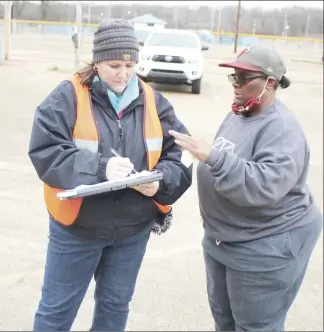  ?? ?? Above, Scarlett Mullins, left, with the Food Bank, reviews details with Inez Marrs before beginning the distributi­on Wednesday in Forrest City. The Food Bank receives help with distributi­on through city and other local agencies. At right, Mark Porter carries a box to a car during the drivethrou­gh distributi­on.