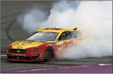  ?? AP/CARLOS OSORIO ?? Joey Logano celebrates with a burnout after winning the Firekeeper­s Casino 400 at Michigan Internatio­nal Speedway.