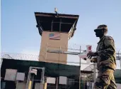  ?? RAMON ESPINOSA/AP 2018 ?? A task force member walks past a detention facility at the Guantanamo Bay U.S. Naval Base.