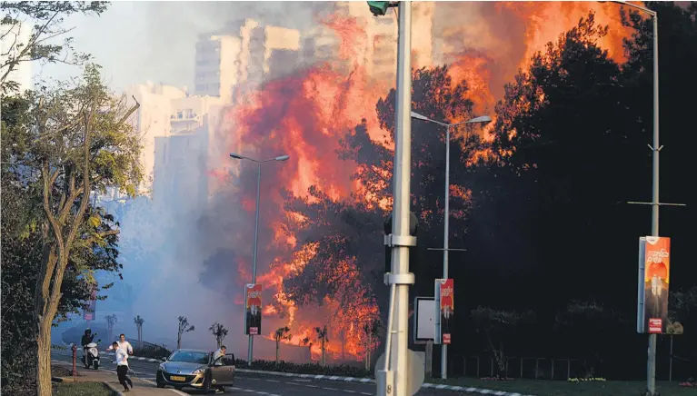  ?? Picture / AP ?? People run for safety as wildfires fanned by dry, windy weather tear through parts of Israel’s third- largest city and stretch firefighte­rs, police and military reservists.