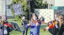  ?? ADRIAN LAM, TIMES COLONIST ?? Cleo Bateman, 8, holds a sign while her fellow music students perform during a protest against SD61 budget cuts which threaten to eliminate nearly all the music teaching positions at Lansdowne Middle School.