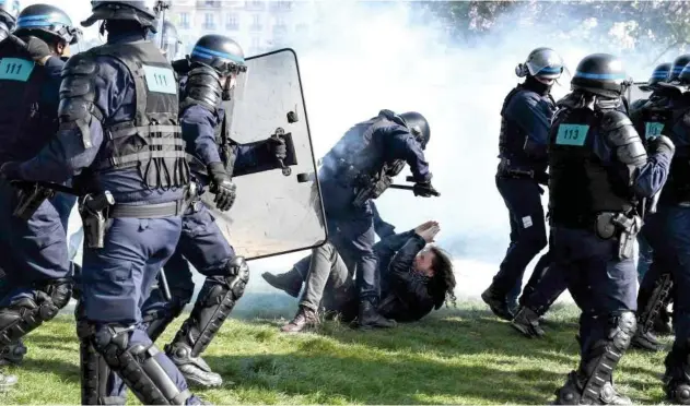  ?? Agence France-presse ?? ↑ A protester reacts on the ground as a police officer stands over him during clashes in Paris on Sunday.