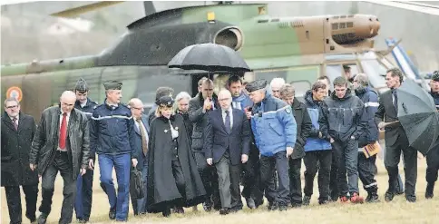  ??  ?? French Interior Minister Bernard Cazeneuve (centre) is sheltered from the rain upon his arrival in Seyne, south-eastern France, near the site where a Germanwing­s Airbus A320 crashed in the French Alps. — AFP photo