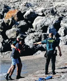  ?? | AFP ?? SPANISH civil guards help a migrant after he arrived swimming to the Spanish enclave of Ceuta from neighbouri­ng Morocco yesterday. More than 80 migrants, including some minors, set off in the early hours of yesterday from beaches a few kilometres south of Ceuta and were detained when they entered the Spanish territory.