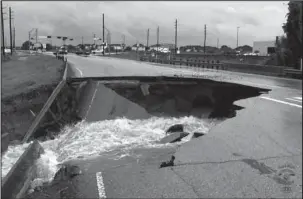  ?? The Associated Press ?? SINKHOLE: In this photo provided by the Rosenberg Police Department, water rushes from a large sinkhole Sunday on Highway FM 762 in Rosenberg, Texas, near Houston. Police say the sinkhole has opened on the Texas highway as Tropical Storm Harvey dumps...