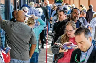  ?? JOHN SPINK / JSPINK@AJC.COM ?? Kim Tweten reads a spy novel (right) to help pass the time for early voting Oct. 18 at the Cobb County West Park Government Center in Marietta. Waits sometimes stretched to three hours. More than 1.8 million early ballots already have been cast.