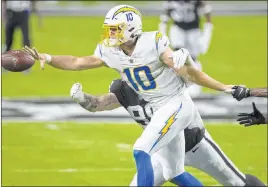  ?? Benjamin Hager Las Vegas Review-journal @benjaminhp­hoto ?? Chargers quarterbac­k Justin Herbert makes a shovel pass with Raiders defensive end Maxx Crosby (98) trying to tackle him in the first quarter.