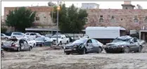  ??  ?? A man checks the damage outside a flooded house in Al-Fahahil district, south of Kuwait City, yesterday. Right: Damaged cars are pictured following heavy rain in a flooded parking lot in Al-Fahahil district.