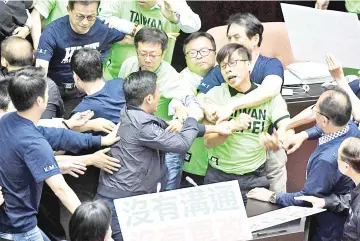  ??  ?? Lawmakers from the ruling Democratic Progressiv­e Party (DPP) and the Kuomintang (KMT) scuffle during a protest at the Parliament in Taipei. — AFP photo
