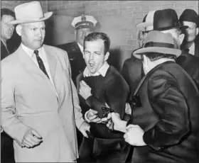  ?? BOB JACKSON — DALLAS TIMES-HERALD VIA AP ?? Lee Harvey Oswald reacts as Dallas night club owner Jack Ruby, foreground, shoots at him from point blank range in a corridor of Dallas police headquarte­rs At left is Detective Jim Leavelle. The longtime Dallas lawman who was captured in one of history’s most iconic photograph­s as he escorted President John F. Kennedy’s assassin moments before he was fatally shot, has died on Thursday. He was 99.