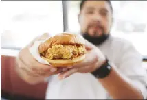  ??  ?? Randy Estrada holds up his chicken sandwich at a Popeyes on Aug 22 in
Kyle, Texas. (AP)