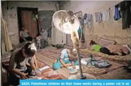  ?? — AFP ?? GAZA: Palestinia­n children do their home works during a power cut in an impoverish­ed area in Gaza City yesterday.