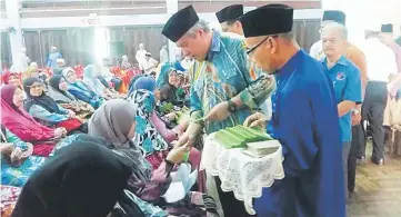  ??  ?? Awang Tengah gives away Hari Raya cash to the single mothers.