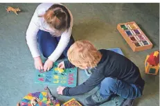  ?? FOTO: DPA ?? Ein Junge und ein Mädchen spielen in einem Kindergart­en auf dem Boden. Eltern bekommen die Beiträge teilweise zurück.