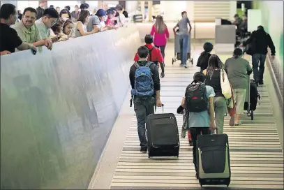  ?? [THE ASSOCIATED PRESS] ?? Travelers make their way up the arrival ramp at the Tom Bradley Internatio­nal Terminal at the Los Angeles Internatio­nal Airport Thursday. Tighter restrictio­ns on travel to the U.S. from six mostly Muslim nations took effect Thursday evening.