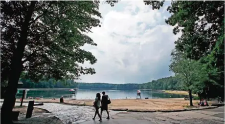  ??  ?? A couple walks along the shore of Walden Pond in Concord, Mass. — AP photos