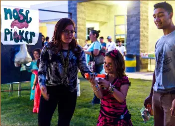  ?? PHOTO VINCENT OSUNA ?? Madison Walker, 7, participat­es in a dart shooting game during Calipatria High School’s fifth annual Fall Harvest Festival held Saturday night.