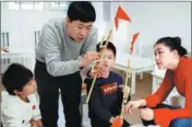  ?? ?? From left: Xu explains to students a sorghum straw work featuring conjoined pavilions, in Tianjin; Xu teaches pupils to make windmill toys at a kindergart­en in Beijing; Xu applies the finishing touches to a sorghum straw piece at his workshop in Hebei province.