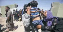  ??  ?? Iraqi security forces embrace members of their families Wednesday at a camp for displaced people in the district of Hajaj after civilians fled the towns because of IS.