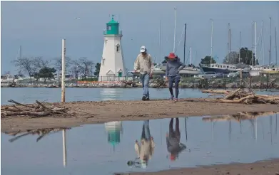  ?? BOB TYMCZYSZYN
TORSTAR ?? Walkers try to negotiatio­n the narrow strips of beach left at Port Dalhousie.