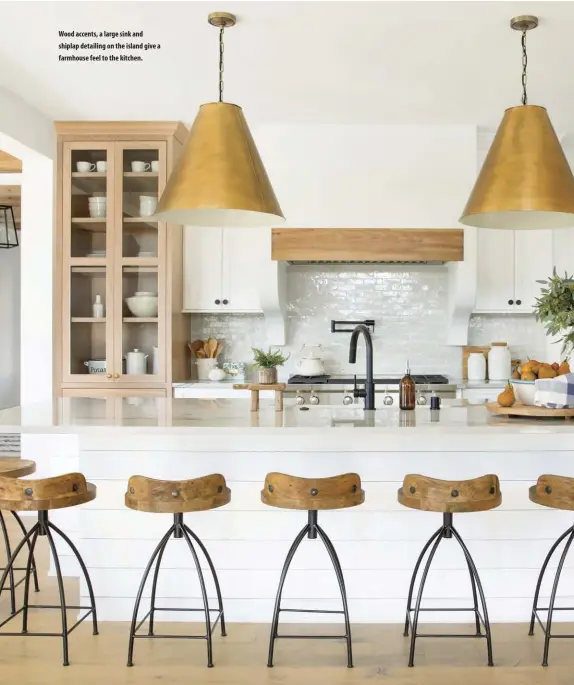  ??  ?? Wood accents, a large sink and shiplap detailing on the island give a farmhouse feel to the kitchen.