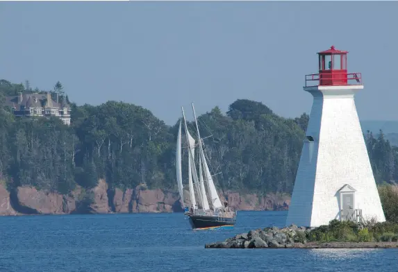  ?? NOVASCOTIA.COM ?? A touring sailboat passes the lighthouse at Baddeck on the Bras d’Or Lake in Cape Breton, N.S. In the background is the former summer home of Alexander Graham Bell.