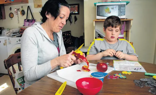  ?? ?? Jenn Spears peels some fruit for her son Jasper, 6, as he does some crafts at their kitchen table on Monday. RYAN TAPLIN • SALTWIRE