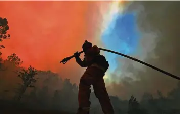  ?? Jose Carlos Fajardo / Associated Press ?? A firefighte­r pulls a hose along while battling the Glass Fire on Sunday in St. Helena, Calif.