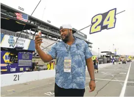  ??  ?? Raiders offensive tackle Marshall Newhouse records a message on a smart phone in pit row before the Toyota/Save Mart 350 at Sonoma raceway on Sunday.