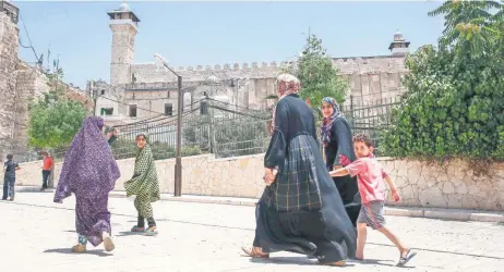  ??  ?? Personas caminan afuera de la Tumba de los Patriarcas (para los judíos) conocida también como la Mezquita Al Ibrahim (para los musulmanes), en Hebrón.