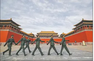  ?? (File Photo/AP/Andy Wong) ?? Soldiers wearing protective face masks march on March 12, 2020, past the closed entrance gates to the Forbidden City, usually crowded with tourists before the coronaviru­s outbreak in Beijing.