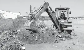  ??  ?? A Bulawayo City Council excavator removes refuse dumped by residents on an undevelope­d stand while trying to open up a storm drain in Selborne Park suburb on Wednesday