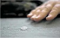  ??  ?? Curran demonstrat­es the hydrophobi­c technology he developed on a treated fabric at his company’s lab.